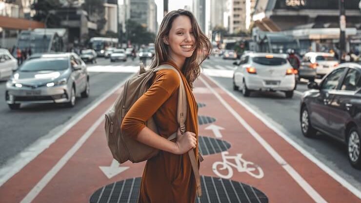 Woman excited about traveling in a city holding a backpack