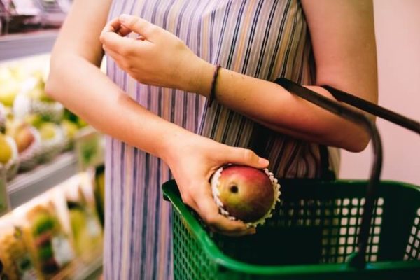 Woman putting asian pear into a green grocery basket