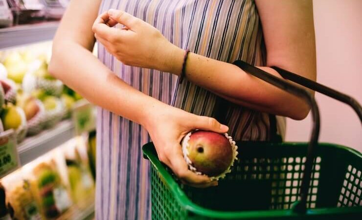 Woman putting asian pear into a green grocery basket