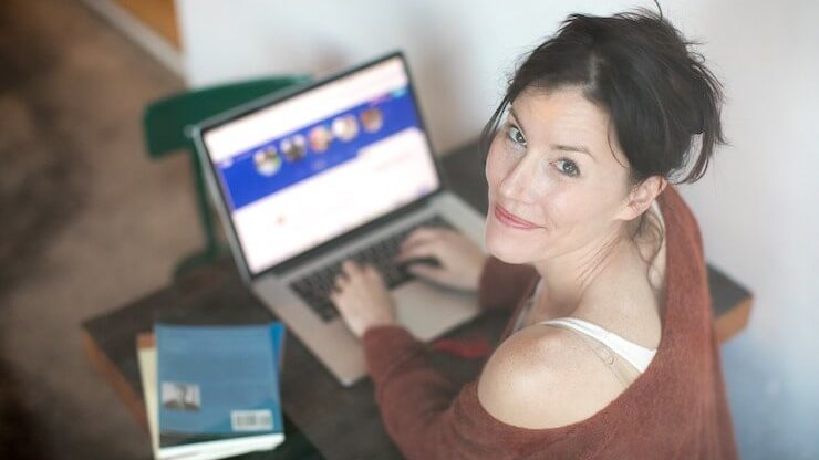 woman shopping online looking to the camera wearing red sweater