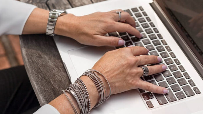 Woman wearing a lot of bracelets and rings taking a survey on her computer