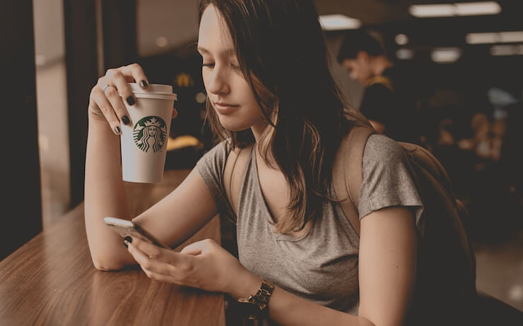 Woman using her phone in an overpriced coffee shop wearing a gold watch