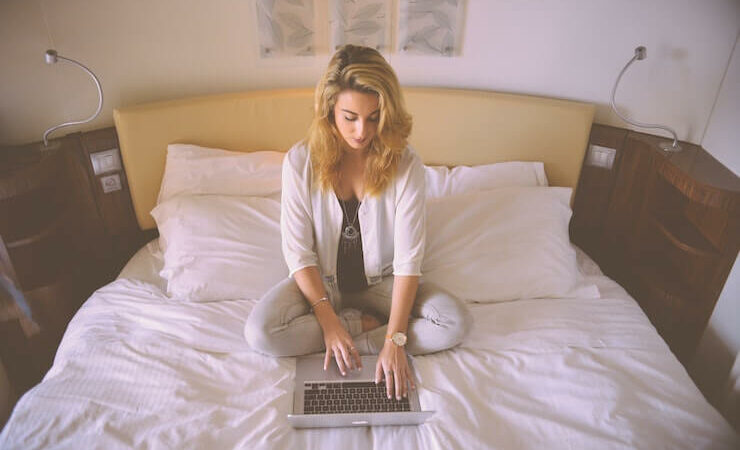 Blonde woman working from home in her bed